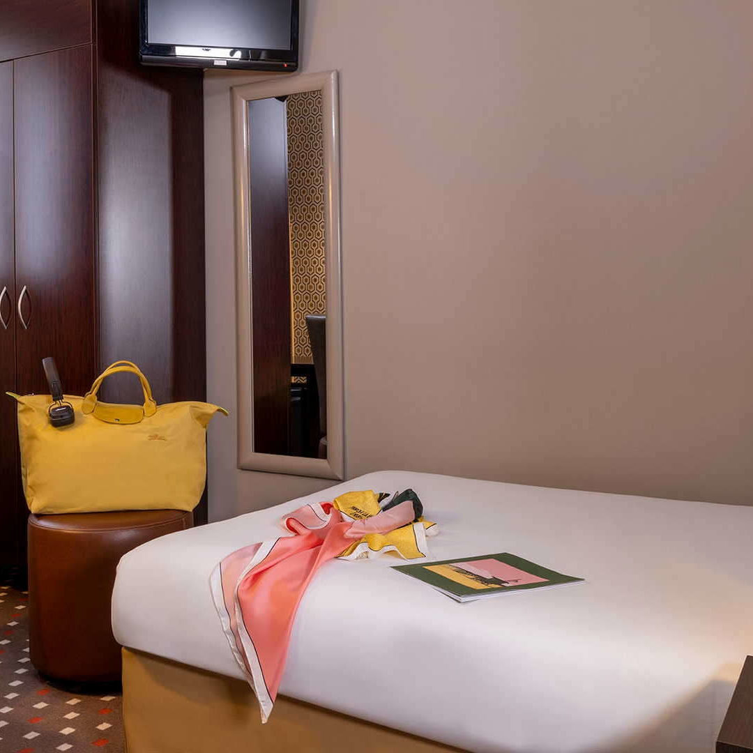 chambre simple avec un sac jaune sur un pouf près du lit – hotel boulevard Saint Germain – Hôtel Abbatial