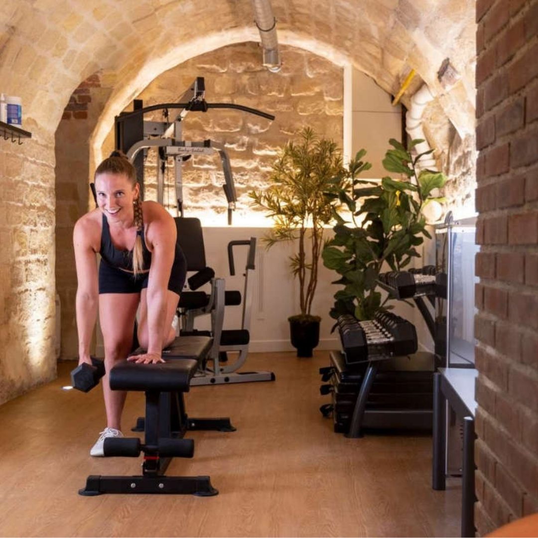Femme qui fait de l'exercice dans la salle de sport de l'hôtel - hôtel près de notre-dame paris – Hôtel Abbatial