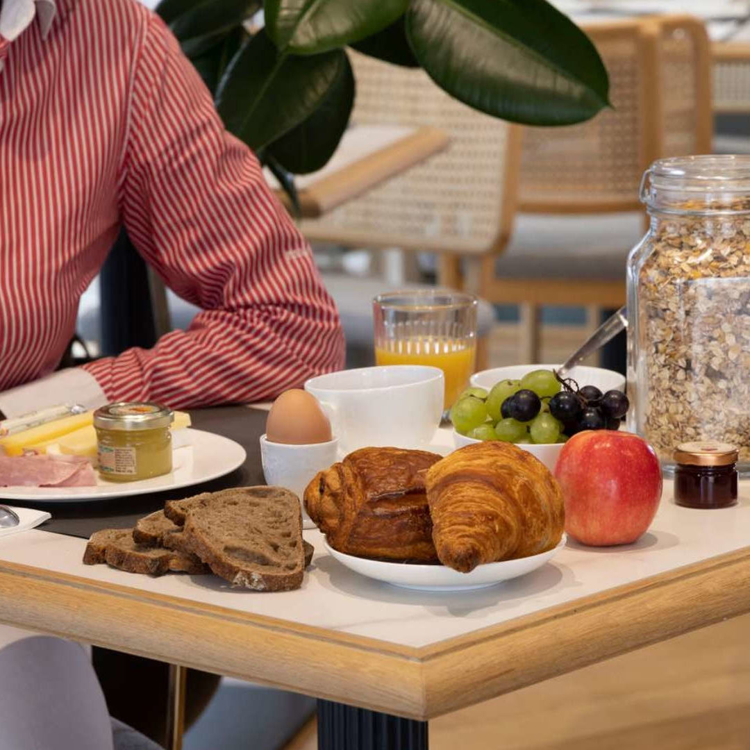 personne lisant un magazine à la table du petit déjeuner - Hôtel près de Panthéon à Paris – Hôtel Abbatial
